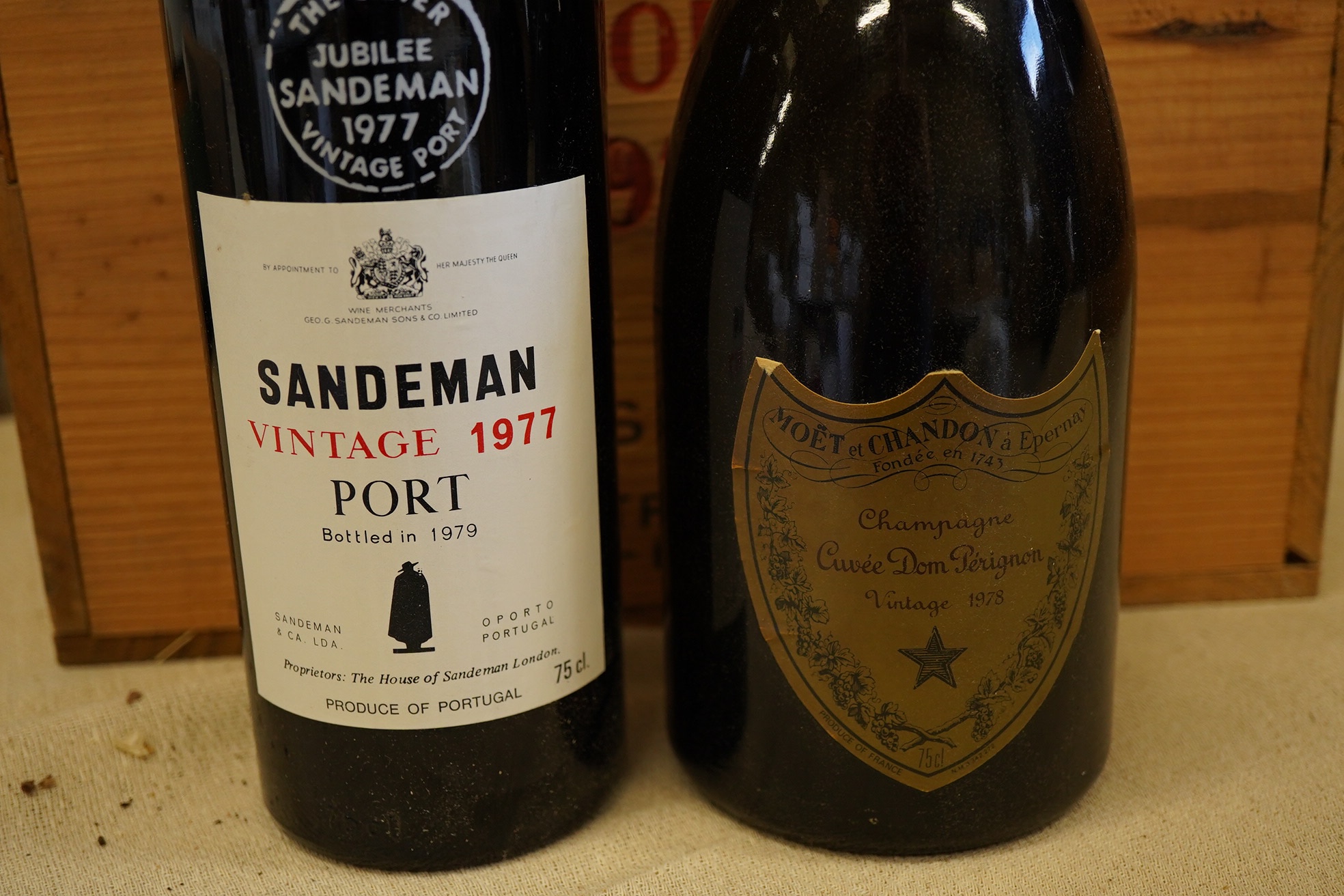 Twelve bottles of 1977 Sandeman vintage port (O.W.C but opened), and a cased bottle of 1978 Dom Perignon champagne